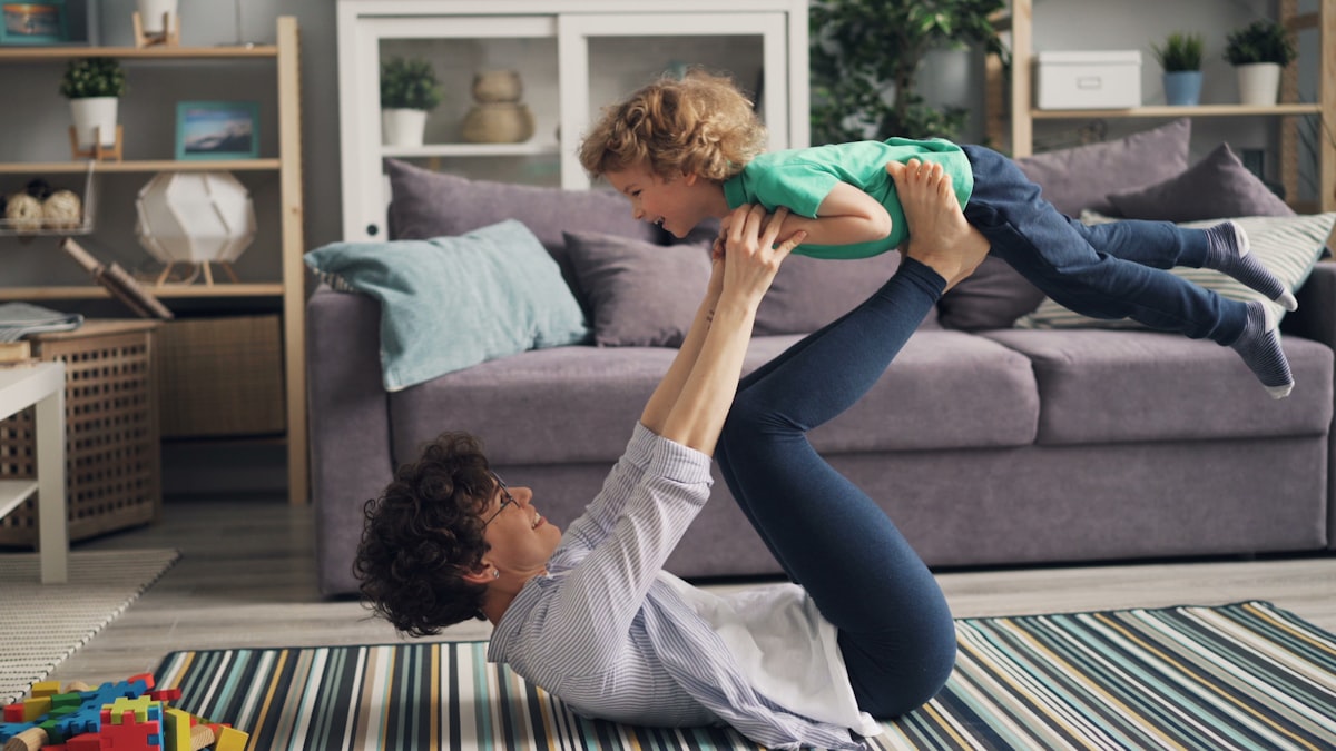 A parent playing with a young child in a bright living room